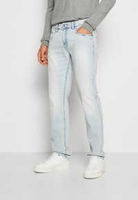 Light blue denim jeans with a relaxed fit, featuring five pockets, a button closure, and stitching detail along the sides.