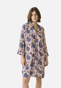 Rochie florală cu un fundal roz și flori albastre, decolteu în V și mâneci trei sferturi. Material ușor, cu detalii plisate.