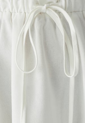 Fascia in tessuto bianco con texture arricciata, dotata di due lunghi nastri. Il materiale è leggero e leggermente traslucido, con una finitura liscia.