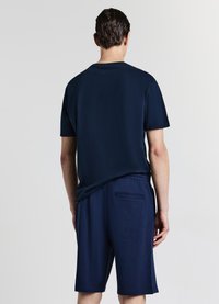 Completo abbinato di camicia a maniche corte e pantaloncini blu navy, realizzato in tessuto morbido, con cintura elastica e tasca posteriore sui pantaloncini.