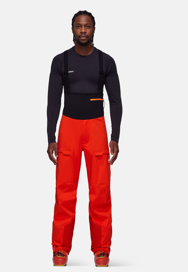 Pantalons de ski orange vif avec bretelles noires ajustables, dotés d'une section de taille noire et de poches cargo sur les cuisses.