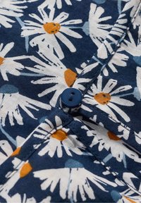 Navy blue fabric with white daisy flowers and orange centers. Features a round navy button and visible stitching along the seams.