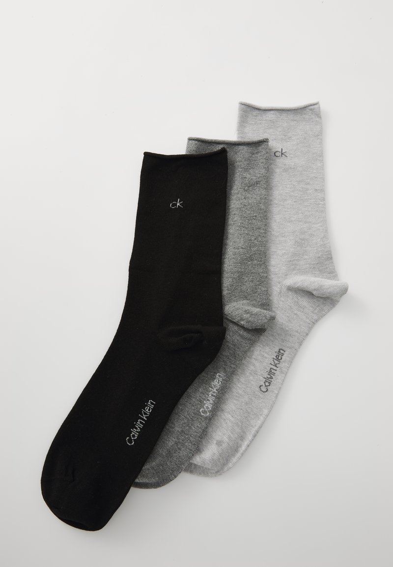Tri par sock zasnovanih iz posadke: ena črna, ena temno siva, ena svetlo siva. Vsaka ima logo Calvin Klein blizu manšete. Gladka tekstura.