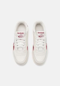 Bele usnjene tene z rdečimi in mornarsko modrimi poudarki, perforiran prednji del, ravne vezalke in oblazinjen jezik z logotipom "Reebok Classic".