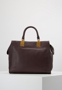 Diep bordeauxleren handtas met een gladde textuur, gestructureerd ontwerp, twee bovenhandvatten en accenten van goudkleurig hardware.