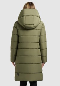 Olivgrüne Steppjacke mit Kapuze, mit gesteppten Abschnitten, langen Ärmeln und einer Länge bis zur Mitte des Oberschenkels. Auffälliges Markenlabel am Saum.