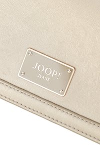 Bež denarnica iz umetnega usnja z teksturirano površino, ki ima kovinsko oznako z napisom "JOOP! JEANS" in dekorativnim šivom.