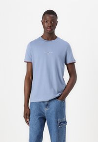 Light blue cotton t-shirt with short sleeves, featuring red and navy striped accents at the cuffs and a small logo on the chest.