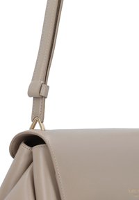 Beige leather shoulder bag with a structured design, featuring a triangular hardware accent and visible stitching for texture detail.