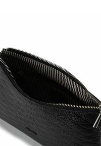 Bolsita negra texturizada con cierre de cremallera y forro de tela a rayas. Cuenta con un tirador de cremallera suave y un interior espacioso.