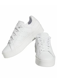 Vita sneakers med en slät läderöverdel, platta snörning, perforerade detaljer och en tjock, vit gummisula.