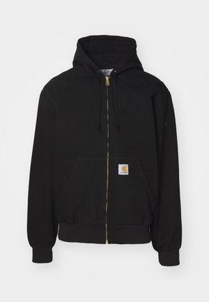 Mustast kummist kapuutsiga jakist. Omab kuldset lukku, reguleeritavat kapuutsi, kotikest ning väikest logo sildi ees.