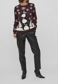 Burgundy stickad tröja med tre pingviner, snöflingor och julgranar. Bärs med svarta mockaläder byxor och klackstövlar.