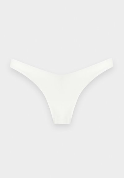 Άσπρο seamless στρινγκ εσώρουχο με μινιμαλιστικό σχέδιο σε ανοιχτό γκρι φόντο.