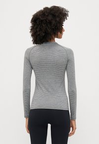 Maglietta a maniche lunghe, aderente, realizzata in tessuto grigio texture con motivo a righe. Presenta un collo arrotondato e dettagli di cucitura sulle spalle.