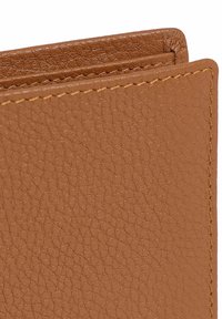 Gros plan sur un portefeuille en cuir tan, présentant une surface texturée, des coutures visibles, des bords repliés et un design simple et épuré.