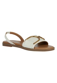 Vit platt sandal med öppen tå, tan sula, slingback-rem och guldmetallspänne på framremmen.