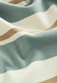 Textília s horizontálnymi pruhmi v svetlomodrej, béžovej a off-white farbe. Materiál má štruktúrovaný, tkaný vzhľad s jemným prevesením.