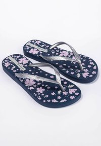 Chanclas de color azul marino con un patrón floral rosa; tirantes plateados texturizados; suela plana de goma; nombre de la marca "Ipanema" en la plantilla.