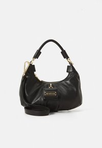 Musta nahkainen käsilaukku, jossa on kaareva muotoilu, kultaiset metalliosat ja logoplakaatti. Sisältää lyhyen kahvan ja irrotettavan olkahihnan.