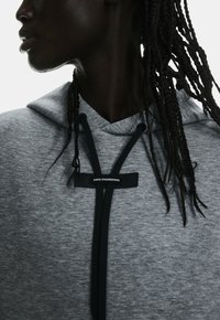 Grauer Hoodie aus weichem Material; verfügt über einen Kordelzug, schwarze Akzente und ein Etikett mit der Aufschrift "SWISS ENGINEERING."