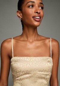 Beige satin dress with leopard print pattern, square neckline, and thin shoulder straps. Smooth texture with subtle sheen.