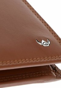 Portefeuille en cuir marron avec des coutures détaillées et un petit emblème argenté ressemblant à une tête d'animal stylisée dans un coin.