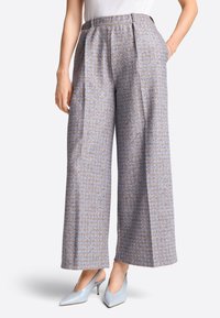 Wide-leg trousers in a blue fabric with a delicate pattern. Features a high waist, pleats, and side pockets. Paired with light blue heels.