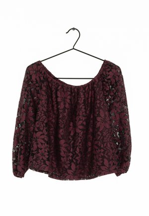 Top bordeaux con motivo in pizzo floreale, vestibilità ampia, design off-shoulder e maniche lunghe. Appeso a un gancio in metallo nero.