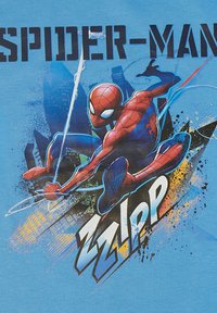 Gráfico de Spider-Man en una camiseta de color azul claro. Presenta un traje rojo y azul, en una pose dinámica, y el texto "ZZIPP" en letras blancas gruesas.