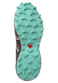 Trailrunningsko med yttersula i mintgrön gummibas med triangelformade dubbar för grepp, dekorerad med en brun sida och en röd logga.