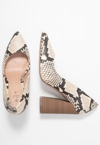 Escarpins à bout pointu en similicuir à motif serpent noir et blanc, dotés d’un talon bloc texturé marron et d’une découpe latérale.