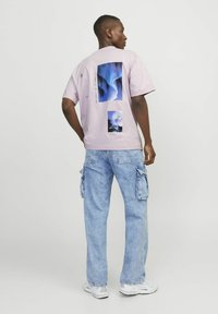 Lila t-shirt med kort ärm och grafiska tryck på baksidan, matchat med ljusblå cargofrukter som har sidfickor och en avslappnad passform.