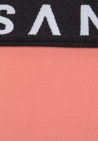 Fascia nera testurizzata con lettering bianco nella parte superiore, sopra una sezione di tessuto corallo liscio e rigato. Il design è minimalista e moderno.