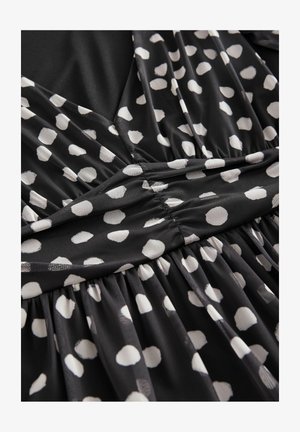 Mustassa kankaita oleva mekko, jossa on valkoisia pilkkuja. Materiaali on pehmeä ja kevyt, ja vyötäröllä on kerrosyksityiskohtia.