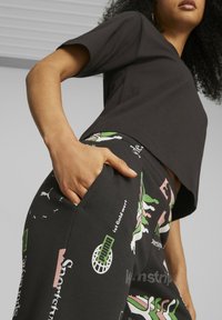 Svart kortärmad t-shirt som är croppad, matchad med svarta byxor med färgglada grafiska mönster och fickor.