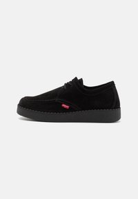 Chaussure à lacets en daim noir avec un bout arrondi, une semelle en caoutchouc texturée et un logo rouge sur le côté. Design simple et texture de surface lisse.