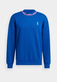 Sweat-shirt bleu à manches longues avec un motif triangulaire rose le long du col et un petit logo blanc Adidas et Juventus sur la poitrine.