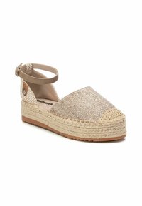 Zapato espadrille beige con parte superior de tejido, puntera redonda, plataforma de yute y correa en el tobillo. Presenta una superficie texturizada y suela marrón claro.