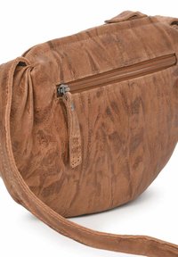 Bolso de cuero marrón con un acabado texturizado, que cuenta con un bolsillo frontal con cremallera y una correa ajustable para llevar. Forma redondeada.