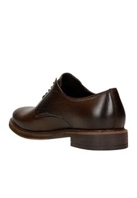 Scarpe eleganti in pelle marrone con punta arrotondata, finitura testurizzata e tacco in legno impilato basso, dotate di chiusura con lacci e contorni morbidi.