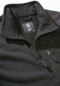 Svart fleecegenser med høy krage, kvart glidelås foran, jevn tekstur og glidelåslomme på siden. Har en logomerketag innvendig.