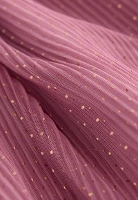 Tissu léger en tulle rose présentant des lignes verticales texturées et de petits points dorés répartis, créant un motif délicat.