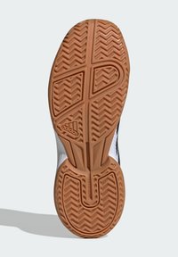 Semelle d'une sneaker avec un fond en caoutchouc texturé dans un motif en chevrons, avec une tige blanche et un logo marqué sur le côté.