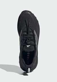 Black athletic shoe with a mesh upper, textured accents, and reflective grey stripes. Features a cushioned sole and prominent "ULTRABOOST" branding.
