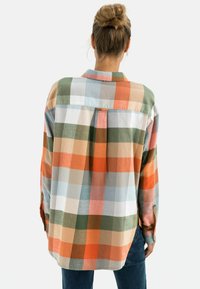 Chemise à carreaux boutonnée avec de grands carrés orange, vert, bleu et beige. Manches longues, pli au dos et ourlet arrondi. Matière en mélange de coton.