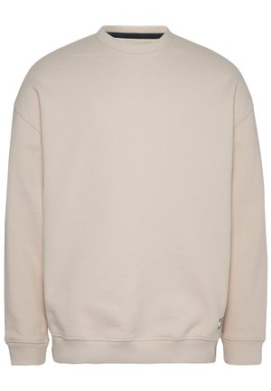 Beżowa bluza z okrągłym dekoltem i długimi rękawami, z prążkowanymi mankietami, dołem i kołnierzem, gładka, z małą metką przy dolnym brzegu.