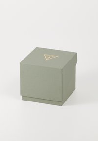 Boîte en carton vert texturé avec un logo triangulaire doré sur le dessus. Forme carrée avec un couvercle et une base solide. Design épuré.