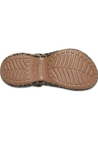 Semelle en caoutchouc marron d'une chaussure avec une surface texturée et des motifs de crampons variés, présentant un bord à imprimé léopard noir sur les côtés.