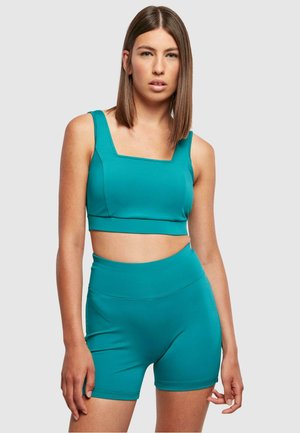 Teal activewear set featuring a square-neck crop top and high-waisted shorts, made from smooth, stretchy fabric with a fitted design.